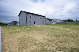 Spacious backyard view showcasing newly built homes and lush green grass.