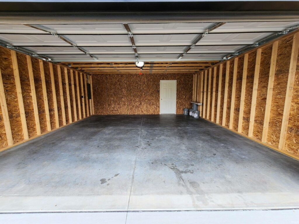 Spacious empty garage interior with concrete floor and wooden walls for storage.