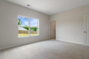 Bright, spacious empty room with natural light and soft carpeted flooring.