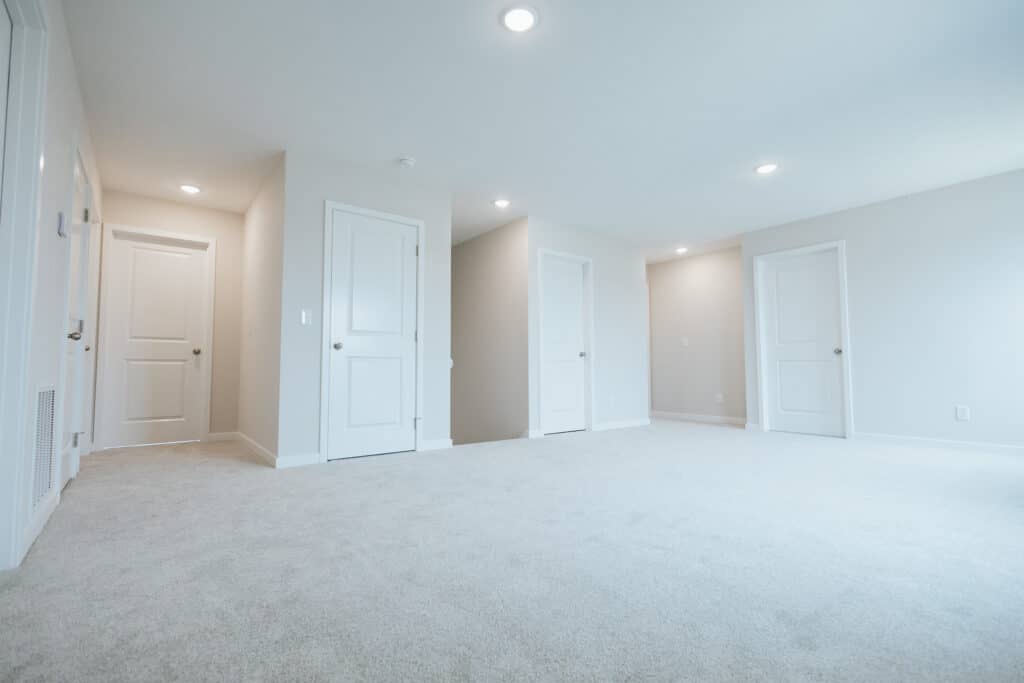 Spacious empty room featuring white doors and neutral carpet, ideal for home design.