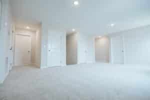 Spacious empty room featuring white doors and neutral carpet, ideal for home design.