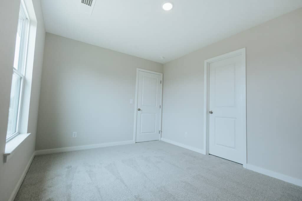 Empty room with two doors and natural light. Ideal for decorating or renovation.
