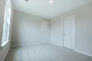 Empty room with two doors and natural light. Ideal for decorating or renovation.