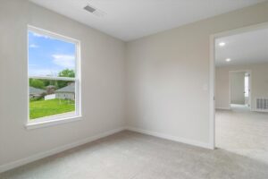 Bright empty room with a large window showcasing a green outdoor view.
