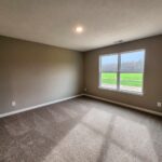 Bright, empty room with a large window overlooking a green field.