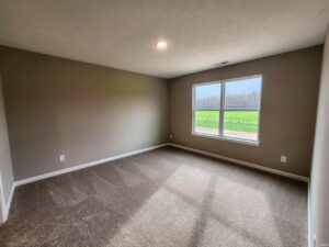 Bright, empty room with a large window overlooking a green field.