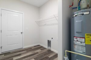 Modern laundry room with storage shelf and water heater for efficient home organization.