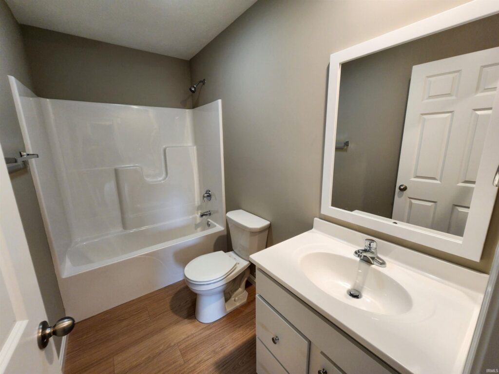 Modern bathroom design featuring a sleek bathtub, toilet, and stylish vanity mirror.