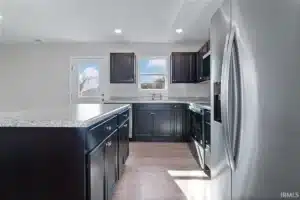 Modern kitchen design featuring dark cabinets and sleek appliances with ample natural light.