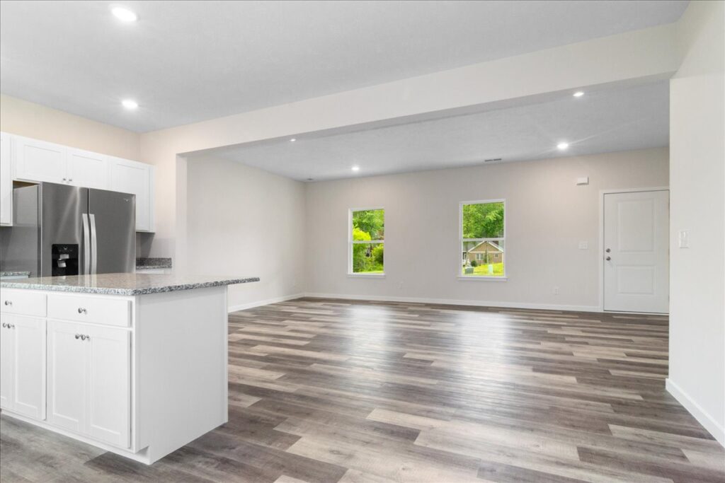 Spacious modern open kitchen and living room with natural light and stylish flooring.