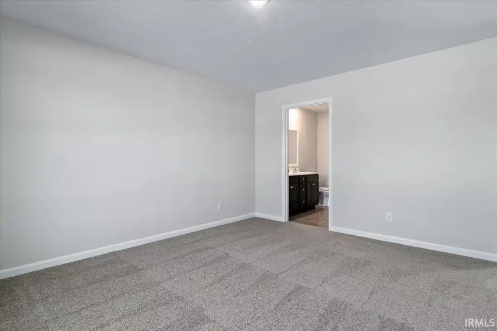 Spacious neutral room design featuring soft carpet and simple decor elements.