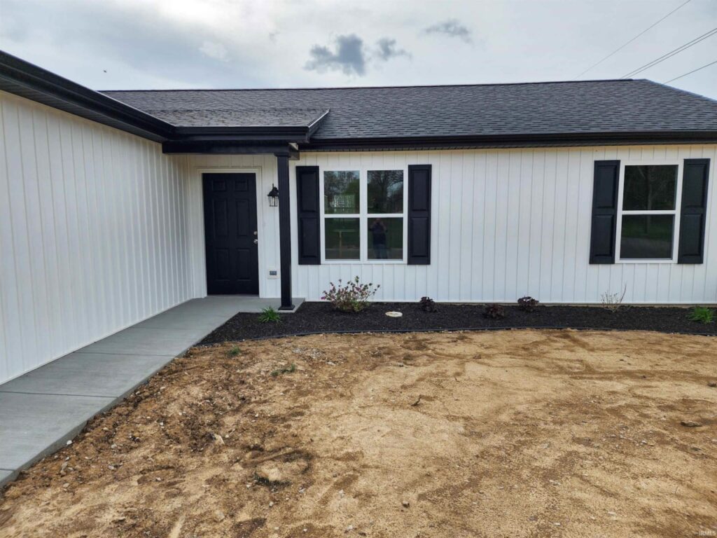 Modern home exterior featuring a stylish black door and landscaped yard.