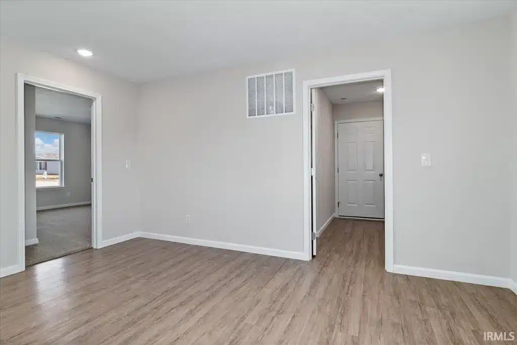 Modern room interior with light wood flooring and neutral-colored walls.