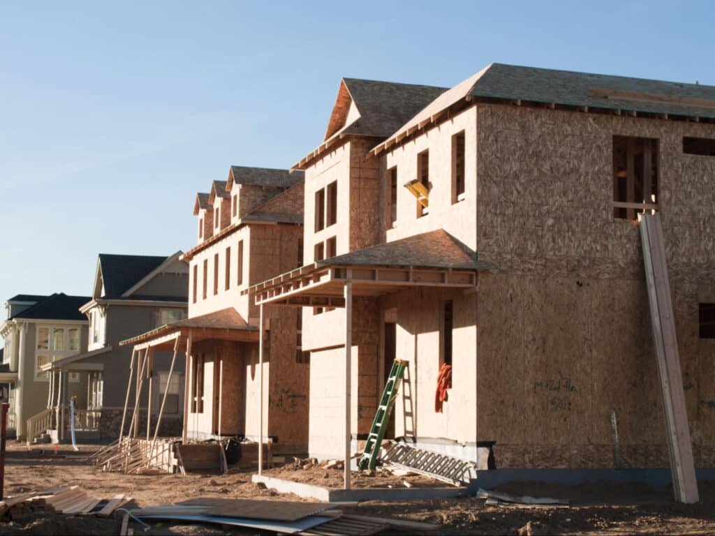 Modern homes being built in a developing neighborhood under clear skies.