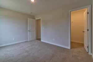 Spacious empty room interior with neutral walls and soft carpet flooring.