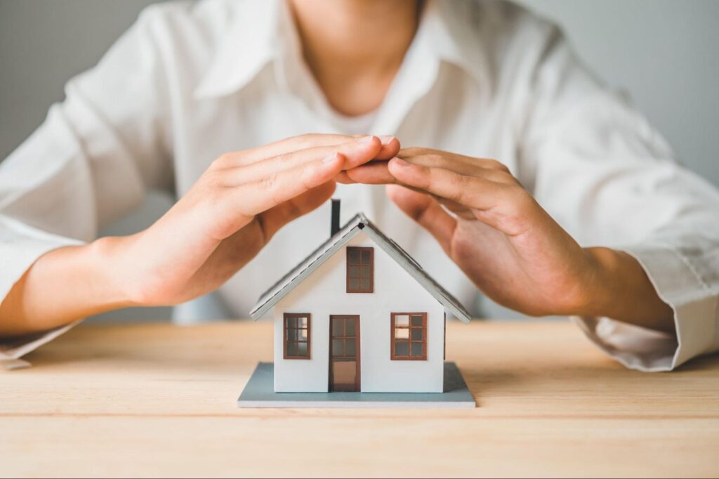 Home warranties concept with closeup of hands over a house