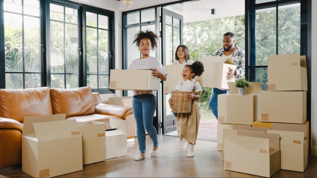 Family unpacking moving boxes in a bright, spacious living room conveying renting vs. buying a home concept