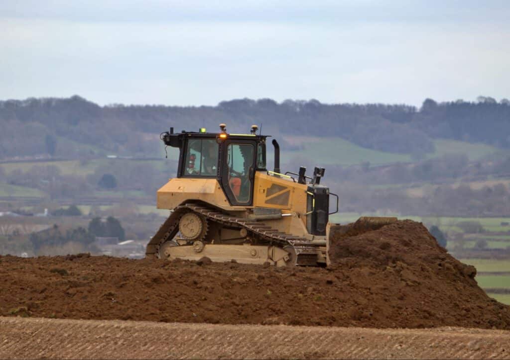 Bulldozer clearing land with hills in the background, illustrating heavy machinery in construction.