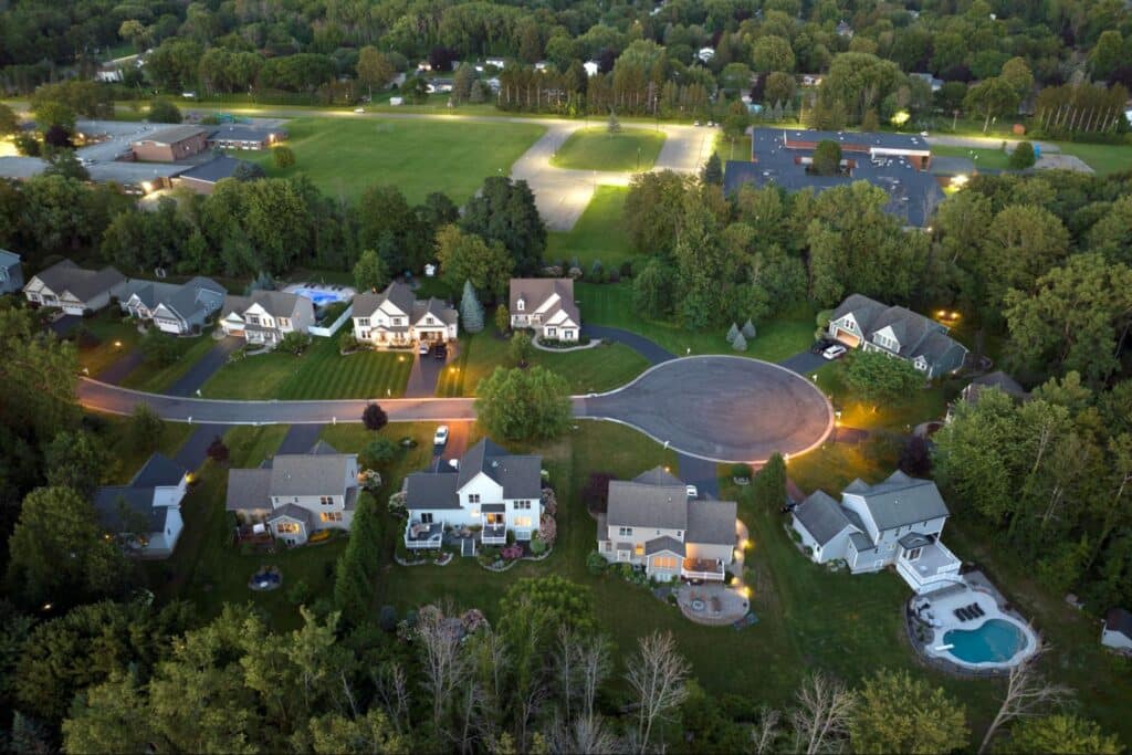 Aerial view of suburban neighborhood showcasing homes and lush green spaces in the evening.