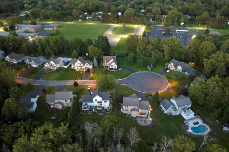 Aerial view of suburban neighborhood showcasing homes and lush green spaces in the evening.