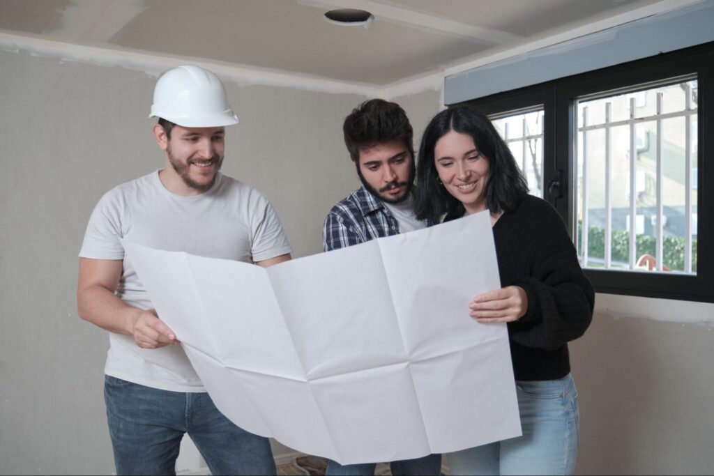 Construction team reviewing building plans together in renovated workspace and providing home building tips