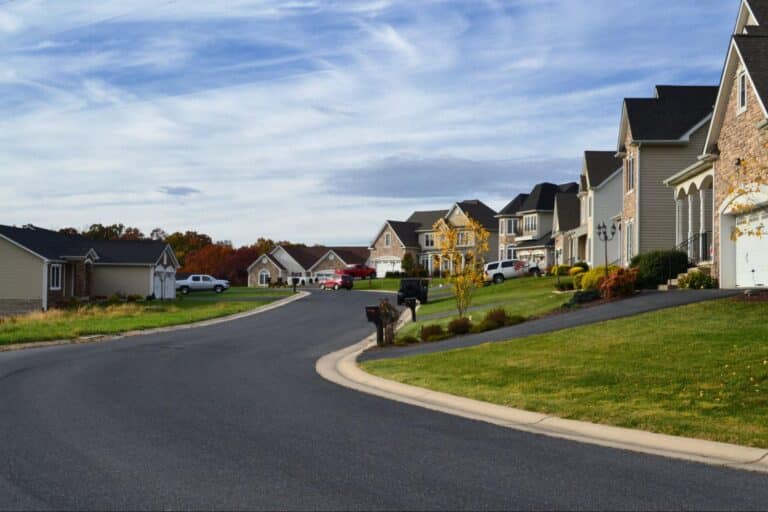 Quiet suburban neighborhood with picturesque homes along a curved street and clear sky.