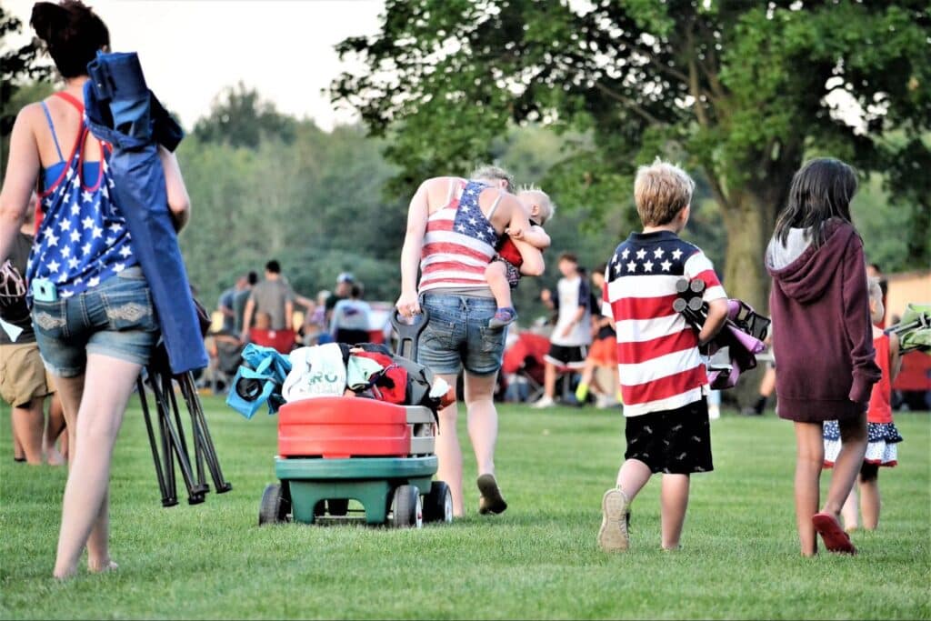 Families enjoying a festive summer day outdoors with patriotic attire and activities conveying homesite considerations like community and events