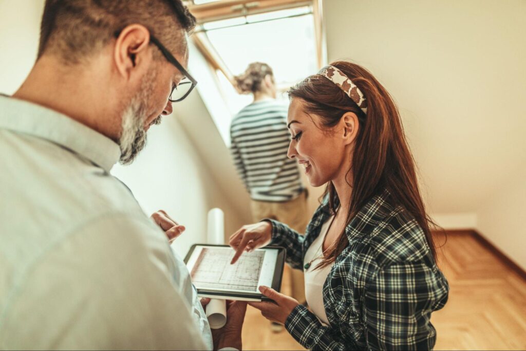 Couple discussing home improvement ideas while reviewing plans on a tablet.