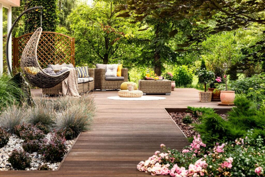 Cozy outdoor patio with woven furniture, vibrant plants, and a relaxing swing chair.