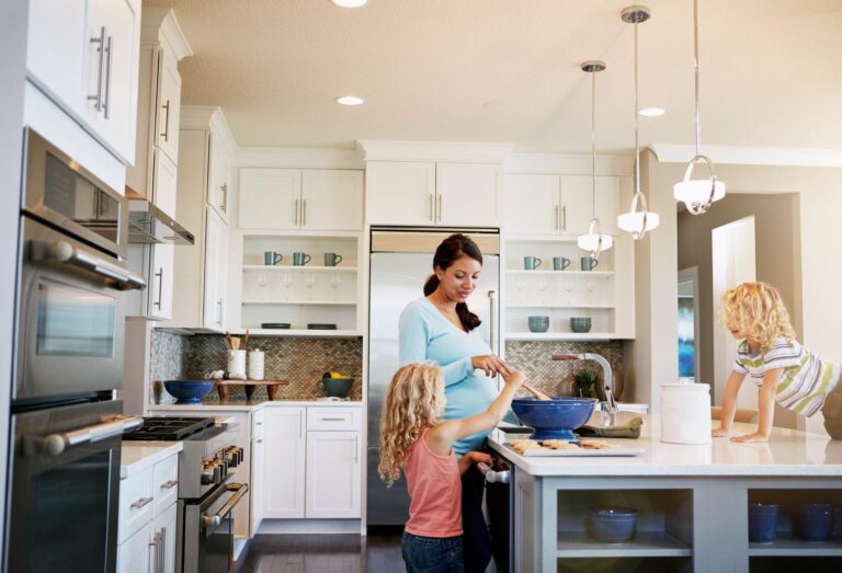 Mother cooking in a modern kitchen with kids enjoying family time.