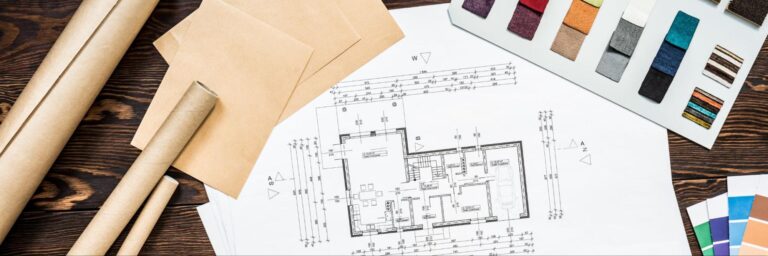 Architectural plans and color palettes for interior design projects are displayed on a wooden table.