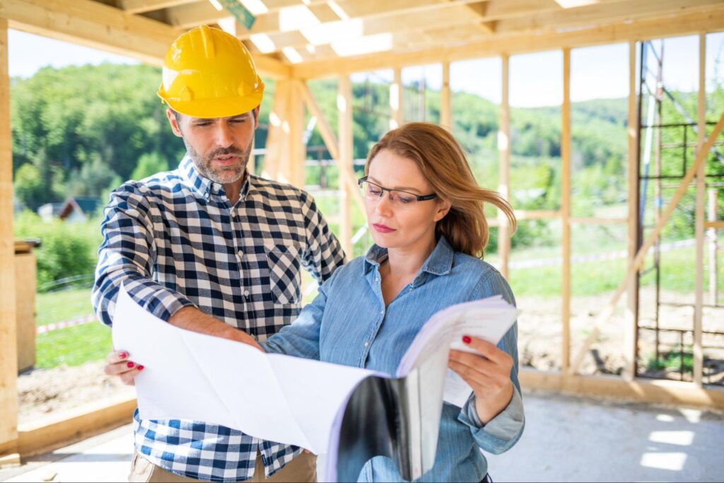 Construction professionals reviewing blueprints at a building site in progress.