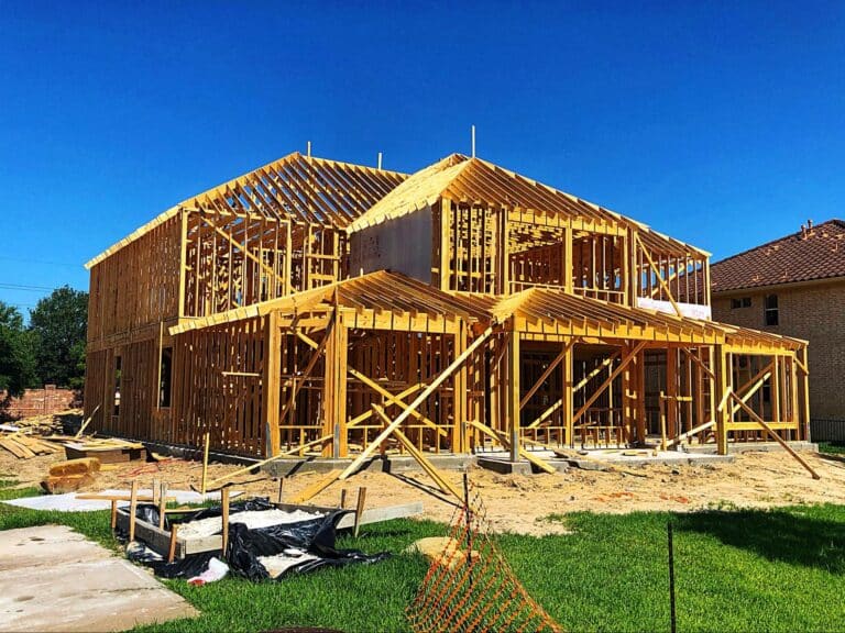 Wooden frame construction of a new home under a bright blue sky.
