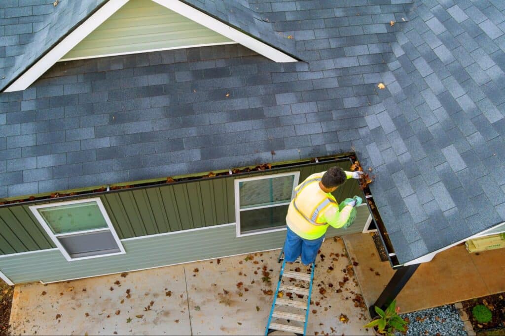 Professional cleaning gutters to ensure home safety and prevent water damage.