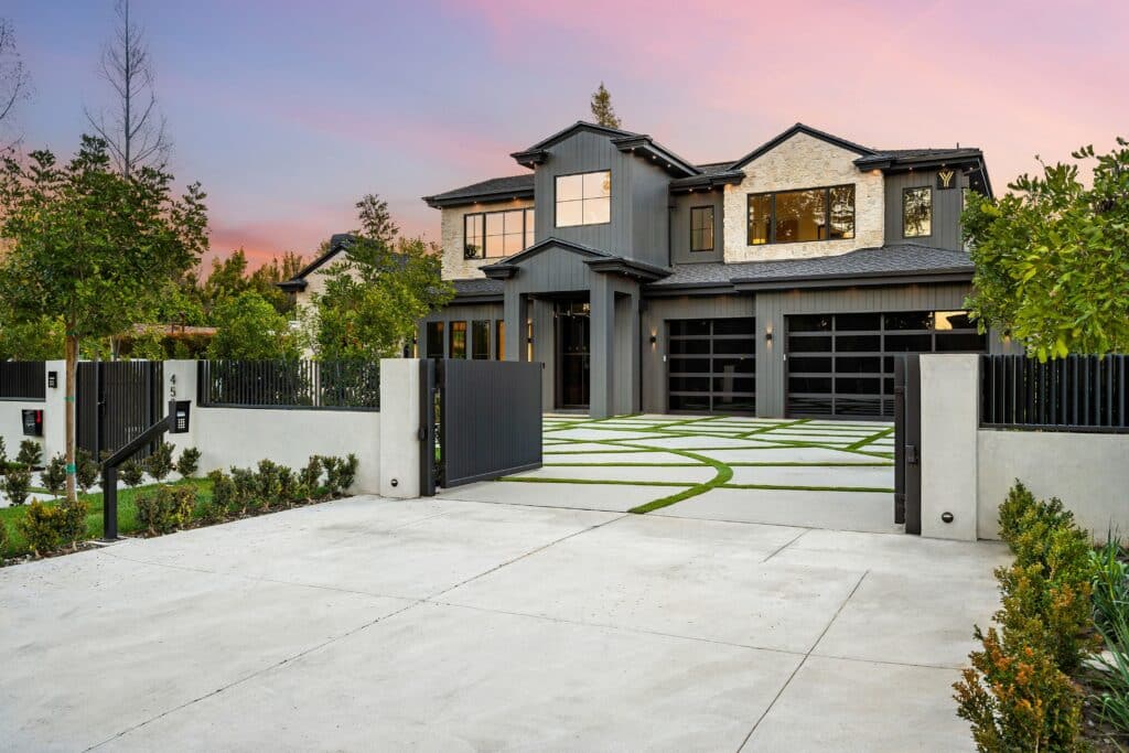 Sleek modern luxury home with landscaped driveway and vibrant sunset backdrop.