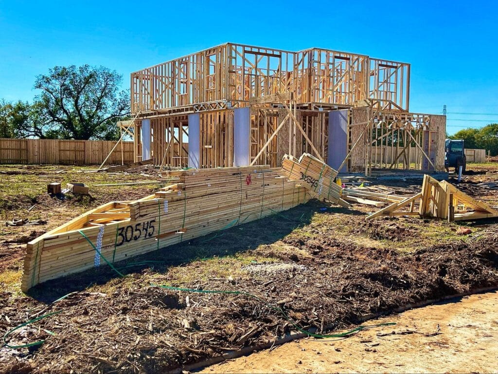 Framed house under construction against a vibrant blue sky.