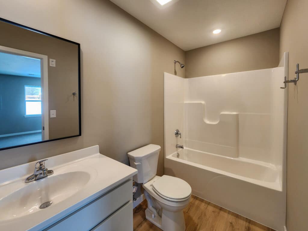 Bright bathroom with modern fixtures, including a shower, vanity, and light colors.