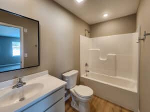 Bright bathroom with modern fixtures, including a shower, vanity, and light colors.