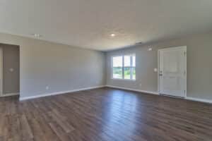 Spacious empty living room with natural light and hardwood floors, ideal for decorating.