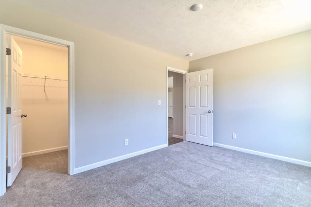 Spacious empty room with doors and light carpeting ready for personalization.