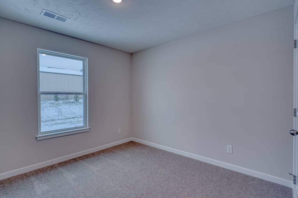 Bright, spacious room with a large window and neutral decor for natural light.