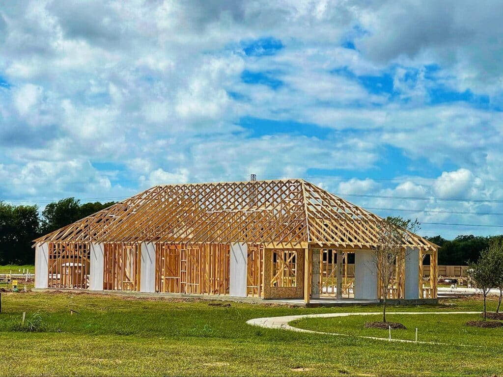 Wooden house framing under a sunny sky, showcasing progress on dream home construction.
