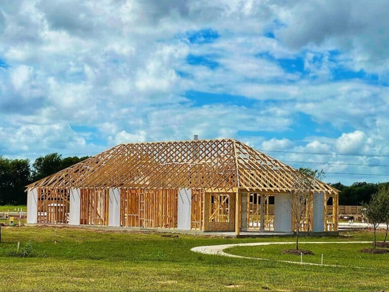 Wooden house framing under a sunny sky, showcasing progress on dream home construction.
