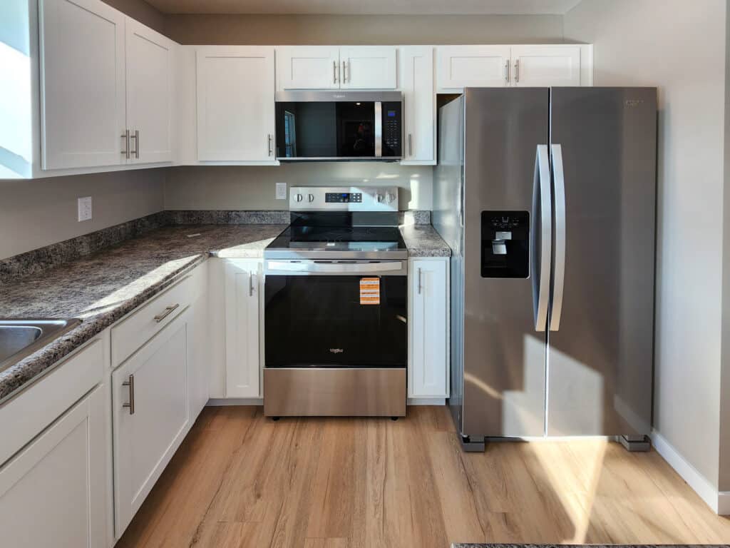 Bright modern kitchen featuring stylish stainless steel appliances and wooden flooring.