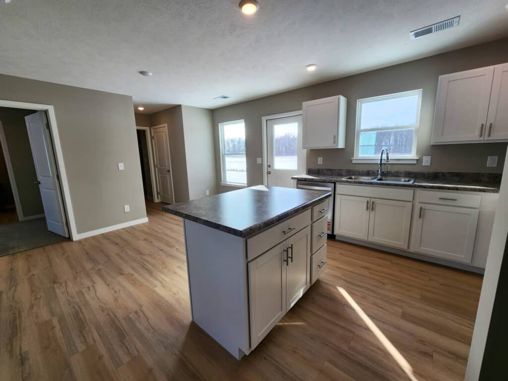 Modern kitchen with white cabinets, island, and bright natural light.
