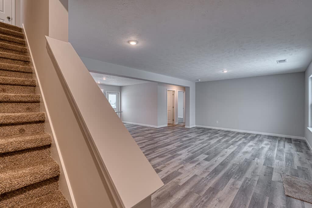 Spacious living room featuring an elegant staircase and modern flooring design.