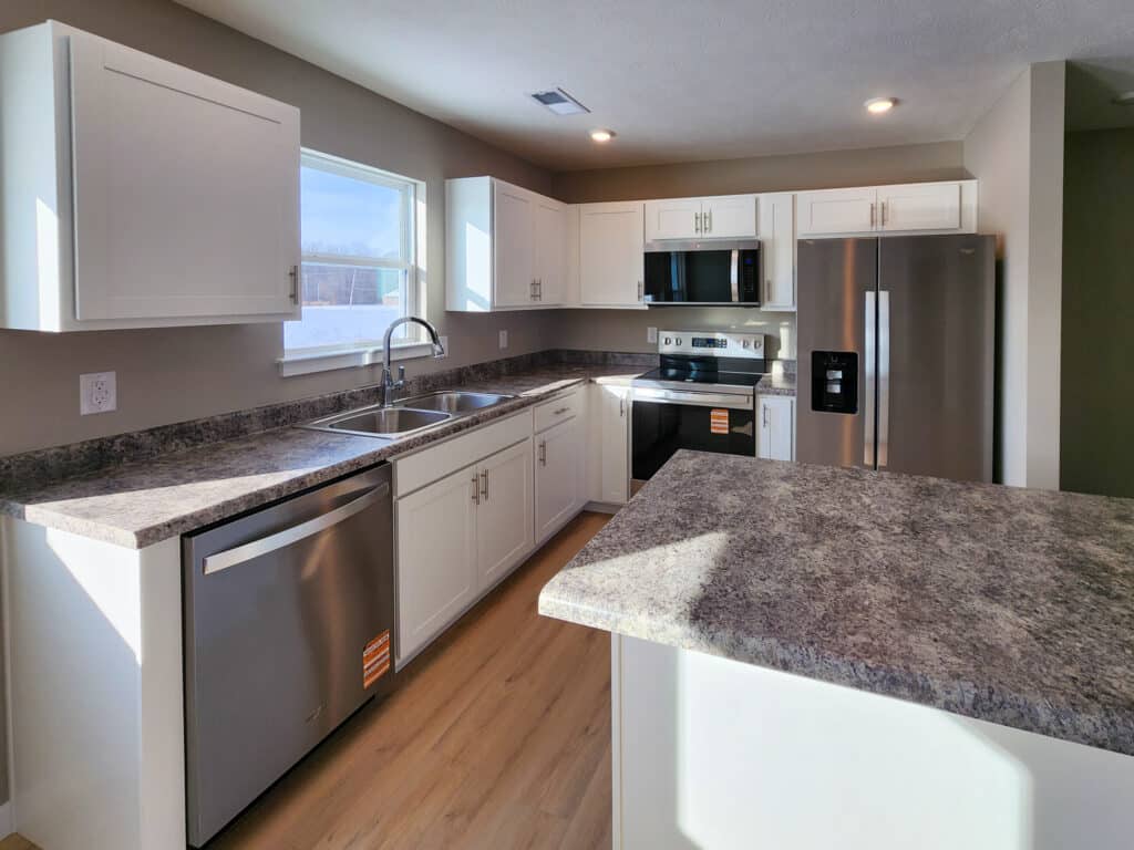 Bright modern kitchen with white cabinets, stainless steel appliances, and ample counter space.