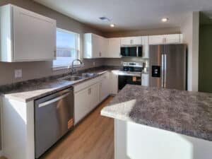 Bright modern kitchen with white cabinets, stainless steel appliances, and ample counter space.