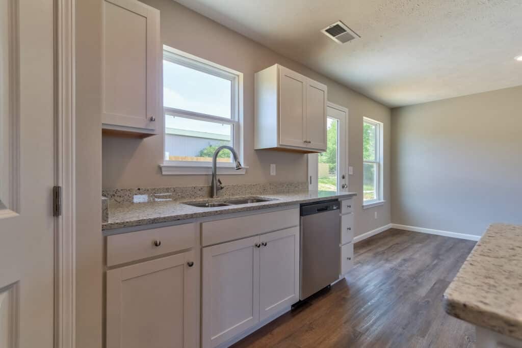 Sleek modern kitchen design with granite countertops and natural light from large windows.