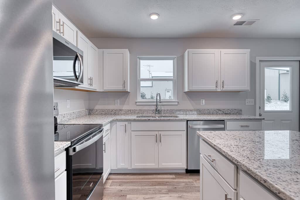 Modern white kitchen featuring granite countertops and stainless steel appliances for stylish cooking.